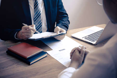 Employer or committee holding reading a resume with talking during about his profile of candidate, employer in suit is conducting a job interview, manager resource employment and recruitment concept.の写真素材