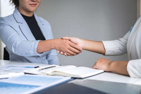 Finishing up a conversation after collaboration, handshake of two business woman leader after successful contract agreement to become a partner, collaborative negotiation partnership.の写真素材