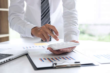 Businessman accountant working analyzing and calculating expense annual financial report balance sheet statement, doing finance making notes on report, Financing Accounting Banking Concept.の写真素材