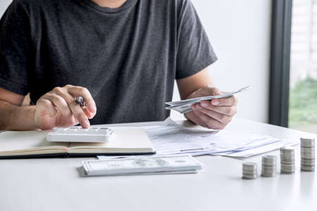 Images of stacking coin pile and Husband using calculator to calculating expenditure receipt bills...
