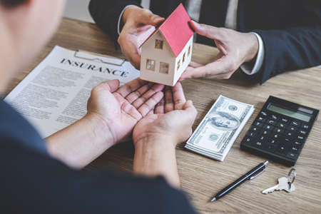 Estate agent giving house and keys to client after signing agreement contract real estate with approved mortgage application form, concerning mortgage loan offer for and house insurance.の写真素材