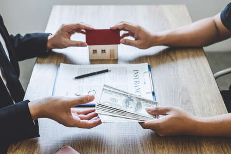 Estate agent giving house and keys to client after signing agreement contract real estate with approved mortgage application form, concerning mortgage loan offer for and house insurance.の写真素材