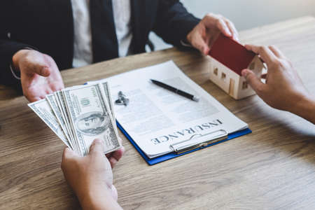Estate agent giving house and keys to client after signing agreement contract real estate with approved mortgage application form, concerning mortgage loan offer for and house insurance.の写真素材