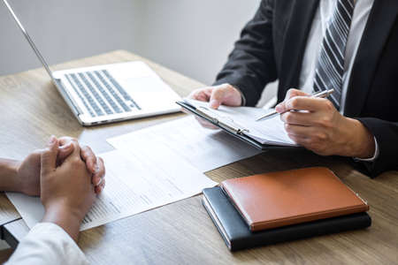 Employer or committee holding reading a resume with talking during about his profile of candidate, employer in suit is conducting a job interview, manager resource employment and recruitment concept.の写真素材