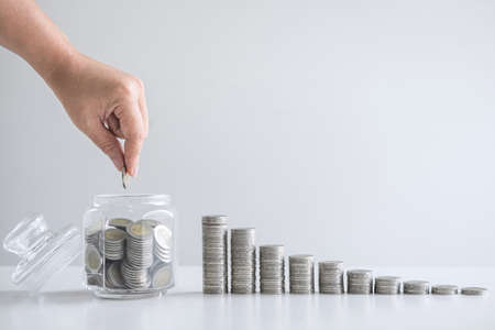 Images of growing stacking coins and Hand putting coin into glass bottle (money box) for planning step up and savings, Saving money for future plan and retirement fund concept.の写真素材