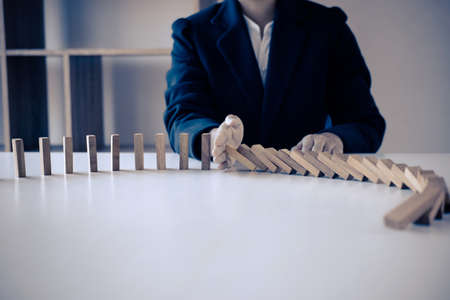 Risk and Strategy in Business, Image of hand stopping falling collapse wooden block dominoes effect from continuous toppled block, prevention and development to stability.の写真素材