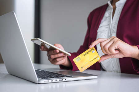 Young woman consumer holding smartphone, credit card and typing on laptop for online shopping and payment make a purchase on the Internet, Online payment, networking and buy product technology.の写真素材