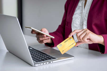 Young woman consumer holding smartphone, credit card and typing on laptop for online shopping and payment make a purchase on the Internet, Online payment, networking and buy product technology.の写真素材