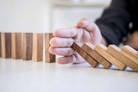 Risk and Strategy in Business, Image of hand stopping falling collapse wooden block dominoes effect from continuous toppled block, prevention and development to stability.の写真素材