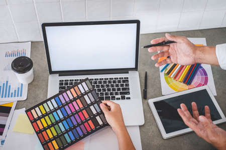 Teamwork of young creative designers working on project together and choose color samples for selection coloring on digital graphic tablet and equipment at workplace.の写真素材
