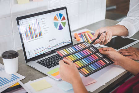 Teamwork of creative designers working on new project and choose color samples for selection coloring on digital graphic tablet with work tools and equipment at workplace.の写真素材
