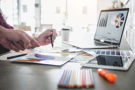 Teamwork of creative designers working on new project and choose color swatch samples for selection coloring on digital graphic tablet with work tools and equipment at workplace.の写真素材