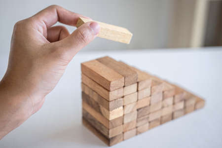 Alternative Risk and Strategy in business to make growth, Image of Business man's hand placing making a wooden block stacking hierarchy on growing to lay the foundation and development to successful.の写真素材