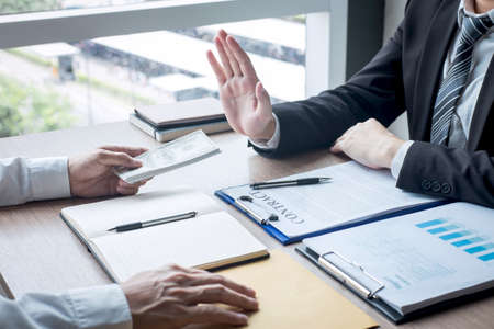 Anti bribery and corruption concept, Business man refusing and don't receive money banknote offer from business people to accept agreement contract of investment deal.の写真素材