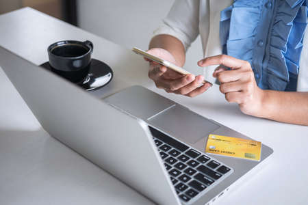 Young woman consumer holding smartphone, credit card and typing on laptop for online shopping and payment make a purchase on the Internet, Online payment, networking and buy product technology.の写真素材
