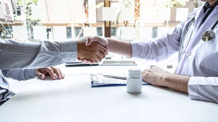 Doctor having shaking hands to congrats with patient after recommend sickness treatment while discussing explaining his symptoms and counsel diagnosis health, healthcare and assistance concept.の写真素材