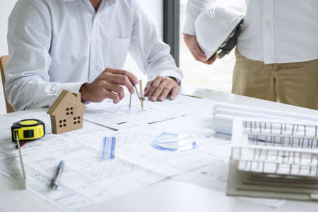 Team of engineering or architect meeting and discussing on blueprint and building model while checking information on sketching for architectural project.の写真素材