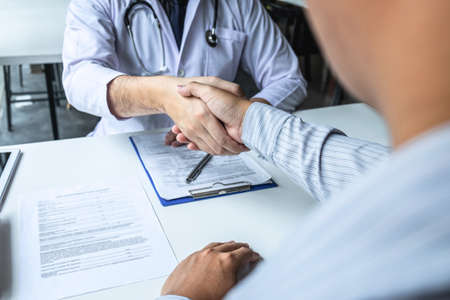 Doctor having shaking hands to congrats with patient after recommend sickness treatment while discussing explaining his symptoms and counsel diagnosis health, healthcare and assistance concept.の写真素材