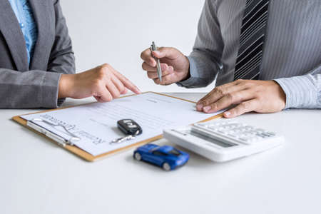 Realtor agent manager pointing rental contract form to businessman client for decide signing to agreement, renting considering vehicle car insurance.の写真素材