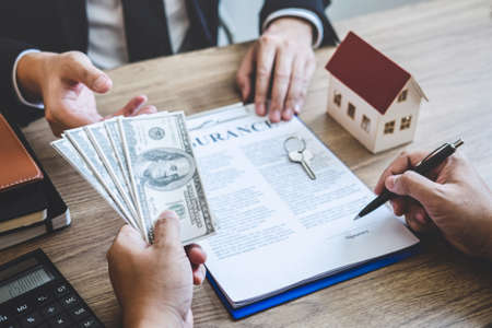 Estate agent broker receive money from client after signing agreement contract real estate with approved mortgage application form, buying or concerning mortgage loan offer for and house insurance.の写真素材