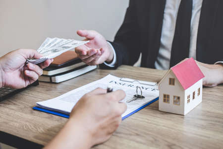 Estate agent broker receive money from client after signing agreement contract real estate with approved mortgage application form, buying or concerning mortgage loan offer for and house insurance.の写真素材