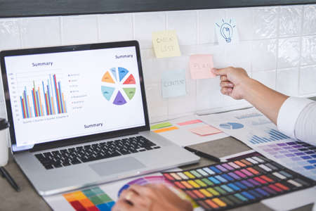 Young creative graphic designer working on project architectural drawing and color swatches, selection coloring on graphic chart with work tools and equipment.の写真素材