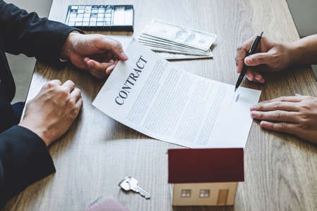 Estate agent broker reach contract form to client signing agreement contract real estate with approved mortgage application form, buying or concerning mortgage loan offer for and house insurance.の写真素材