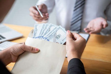 Dishonest cheating in illegal money, Business woman giving bribe money the form of dollar bills to while give success the deal to contract agreement, Bribery and corruption concept.の写真素材