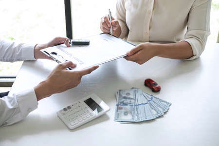 Car rent agent manager holding key of new car giving to woman client after signing good deal agreement contract, renting considering vehicle.の写真素材