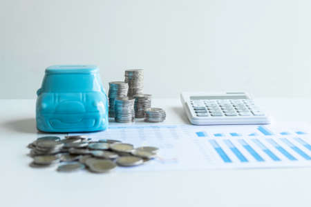 Images of stacking coins pile and blue smiling piggy bank to growing and savings with money box, Saving money for future plan and retirement fund concept.の写真素材