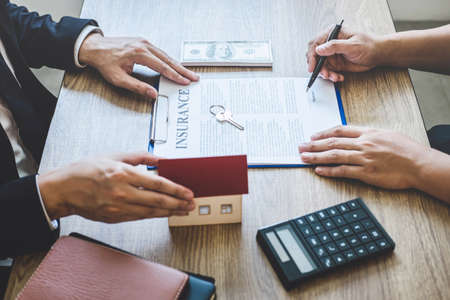 Estate agent giving house and keys to client after signing agreement contract real estate with approved mortgage application form, concerning mortgage loan offer for and house insurance.の写真素材