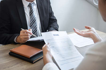 Employer or committee holding reading a resume with talking during about his profile of candidate, employer in suit is conducting a job interview, manager resource employment and recruitment concept.の写真素材