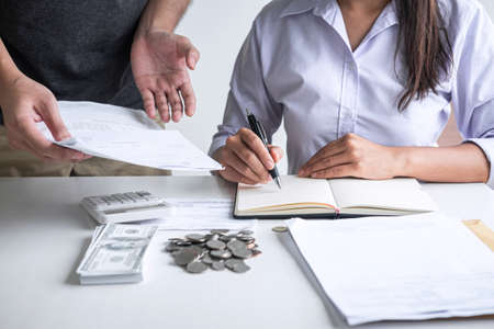 Images of Husband and wife using calculator to calculating expenditure receipt bills of various activity cost and expenses in home office and written make report to plan of spent in future.の写真素材