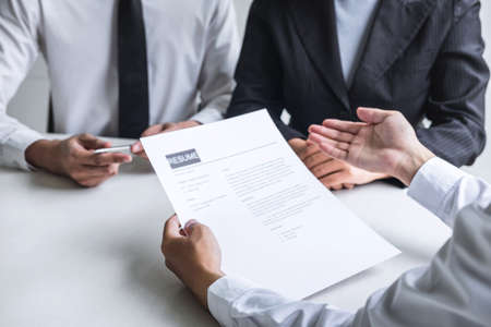 Employer or committee holding reading a resume with talking during about his profile of candidate, employer in suit is conducting a job interview, manager resource employment and recruitment concept.の写真素材