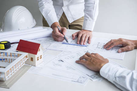Team of engineering or architect meeting and discussing on blueprint and building model while checking information on sketching for architectural project.の写真素材