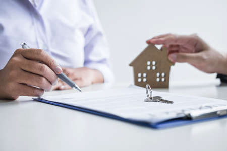 Estate agent broker reach contract form to client signing agreement contract real estate with approved mortgage application form, buying or concerning mortgage loan offer for and house insurance.の写真素材