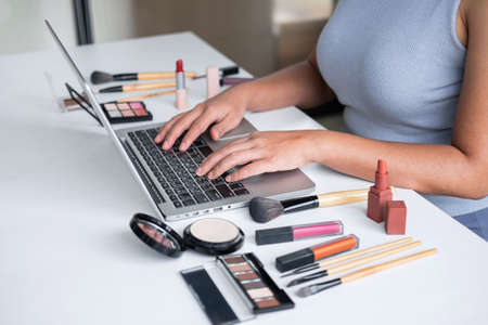 Business online on social media, Beautiful woman is watching online blogger tutorial on laptop, showing present tutorial beauty cosmetic using product makeup.の写真素材
