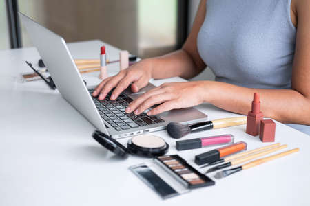 Business online on social media, Beautiful woman is watching online blogger tutorial on laptop, showing present tutorial beauty cosmetic using product makeup.の写真素材