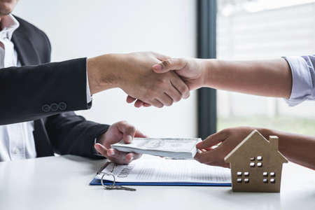 Image of successful deal of real estate, Broker and client shaking hands after signing contract approved application form, concerning mortgage loan offer for and house insurance.の写真素材