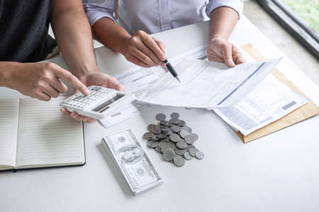 Images of Husband and wife using calculator to calculating expenditure receipt bills of various activity cost and expenses in home office and written make report to plan of spent in future.の写真素材