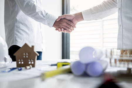 Handshake of collaboration, Construction engineering or architect discuss a blueprint and building...