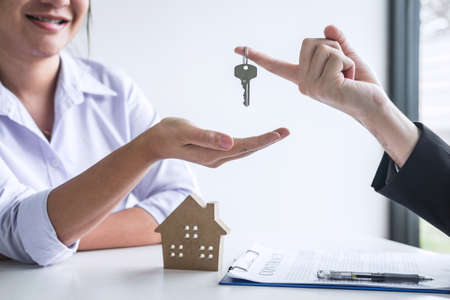 Estate agent giving house keys to client after signing agreement contract real estate with approved mortgage application form, concerning mortgage loan offer for and house insurance.の写真素材
