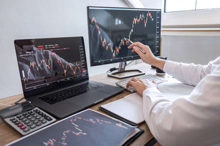 Stock exchange market concept, Business investor trading or stock brokers having a planning and analyzing with display screen and pointing on the data presented and deal on a stock exchange.の写真素材