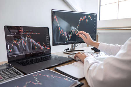 Stock exchange market concept, Business investor trading or stock brokers having a planning and analyzing with display screen and pointing on the data presented and deal on a stock exchange.の写真素材