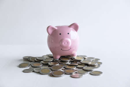 Images of stacking coins pile and pink smiling piggy bank to growing and savings with money box, Saving money for future plan and retirement fund concept.の写真素材