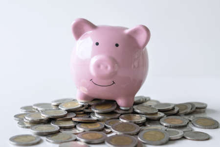 Images of stacking coins pile and pink smiling piggy bank to growing and savings with money box, Saving money for future plan and retirement fund concept.の写真素材