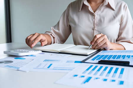 Business woman accountant financier working audit and calculating expense financial annual report balance sheet statement, doing finance checking document and making notes on report paper.の写真素材