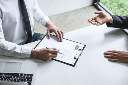 Employer or committee holding reading a resume with talking during about his profile of candidate, employer in suit is conducting a job interview, manager resource employment and recruitment concept.の写真素材