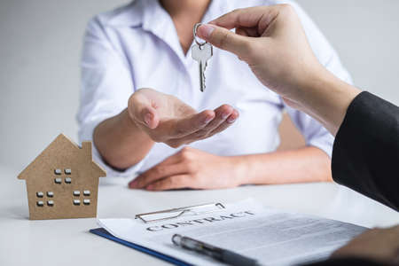 Estate agent giving house keys to client after signing agreement contract real estate with approved mortgage application formの写真素材