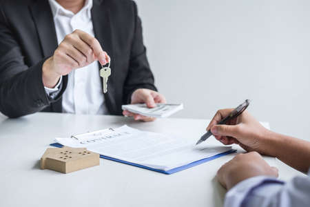 Estate agent giving house keys to client after signing agreement contract real estate with approved mortgage application formの写真素材